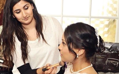 Image of Komal, make up artist, using a make up brush on the face of a bride client