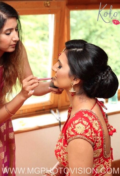 Image of Komal, make up artist, adding lipgloss to an Asian bride's lips