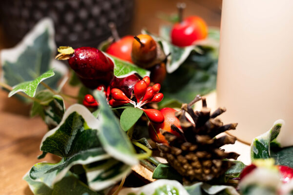 Image of table centre with faux berries, pinecones and variegated ivy