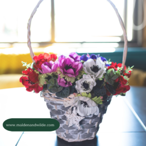 Basket of flowers in summer colours of pink, purple and red