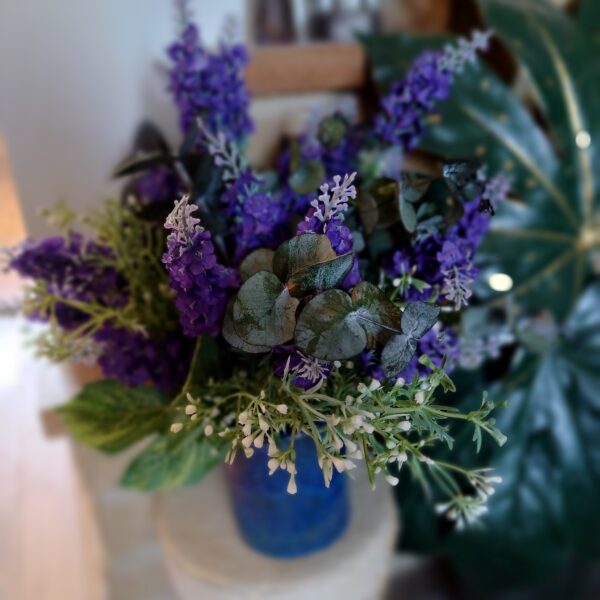 Close up image of silk lavender spears in a ceramic blue vase