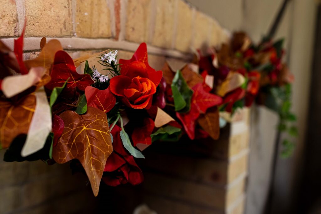 Close up of silk flowers in autumn mantel garland, orange and red