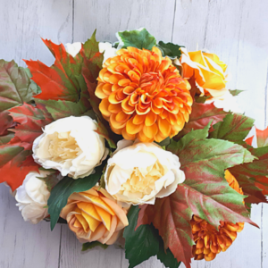 Image of tablecentre with bronze coloured dahlia, cream peonies and orange yellow roses withautumn leaves