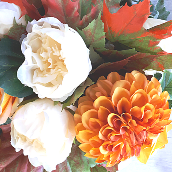 Close up photo of bronze coloured silk dhalia and cream silk peonies