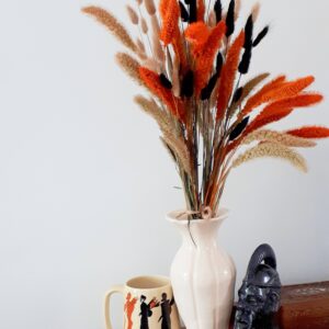 Vase of harvest grasses in orange, black and neutral