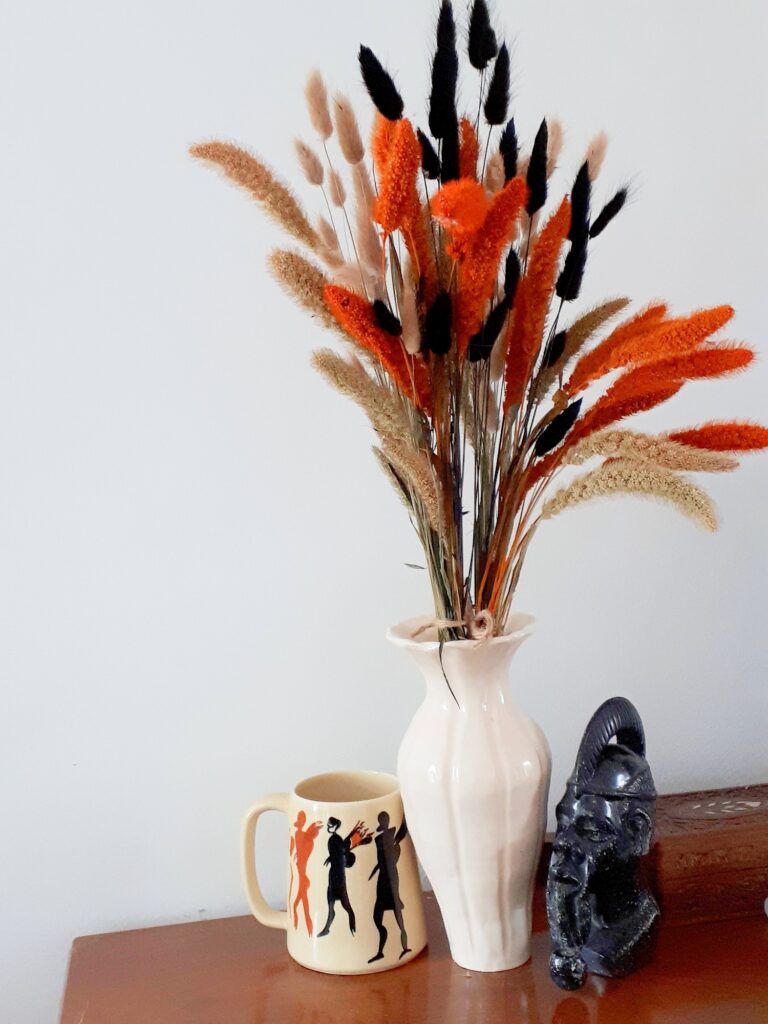 Vase of harvest grasses in orange, black and neutral