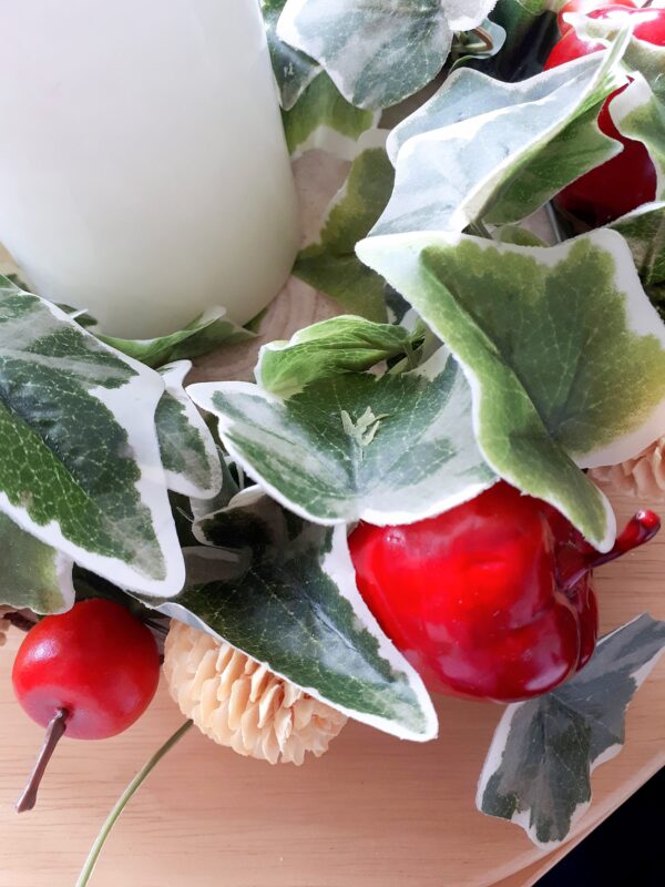 Detail of variegated ivy, red apples and mini bleached pine cones in a festive table centre