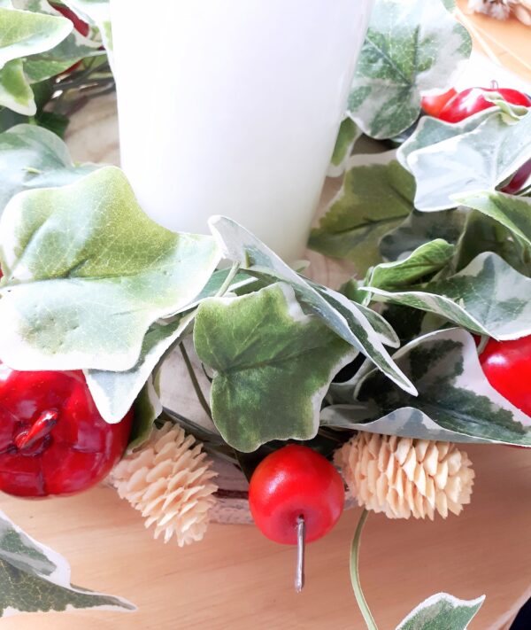 Detail of variegated ivy, red apples and mini bleached pine cones in a festive table centre