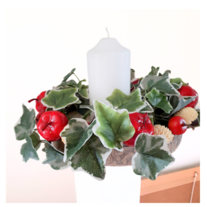 Image of table centre with variegated ivy, shiny red apples and mini bleached pine cones