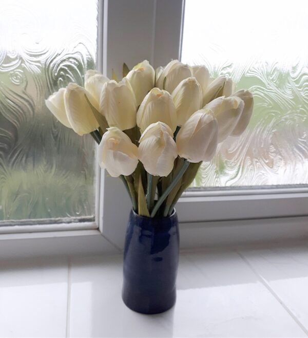 Bunch of cream silk tulips in a blue bud vase