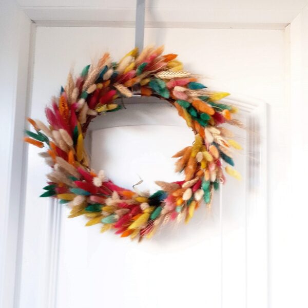 Image of a summer wreath made of dried grasses, dyed in many colours