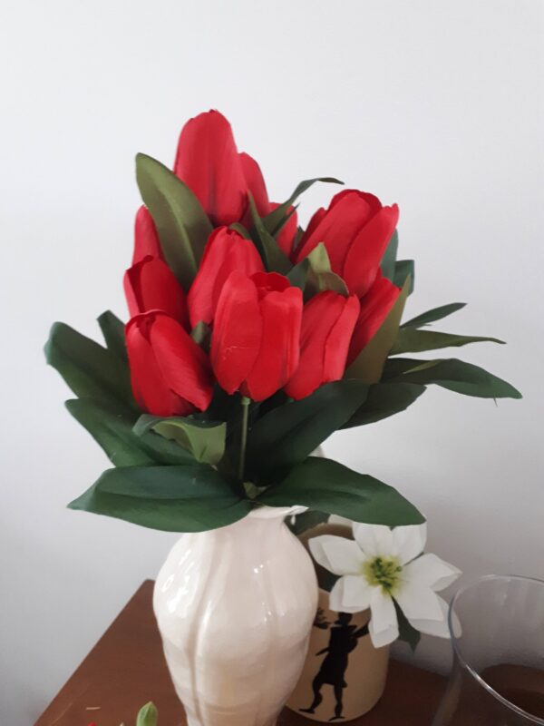 Red tulips in a tall white vase