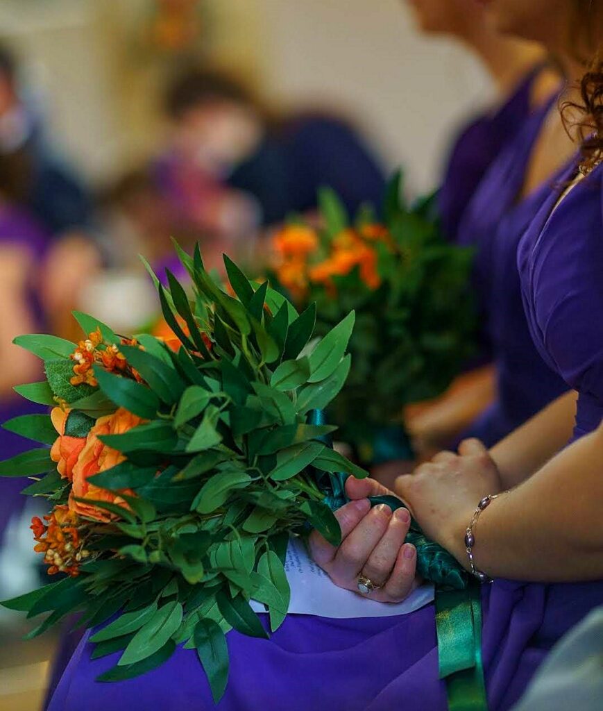 Image of bridesmaids' posies of orange silk flowers and deep green silk foliage