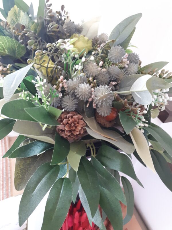 Image of table centre with green foliage, thistles, faux acorns and natural pinecones.