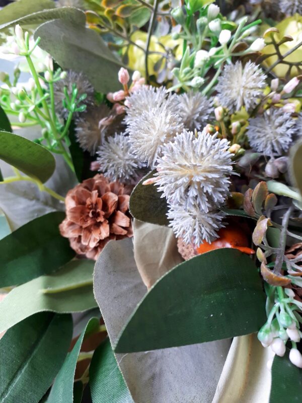 Image of table centre with green foliage, thistles, faux acorns and natural pinecones.