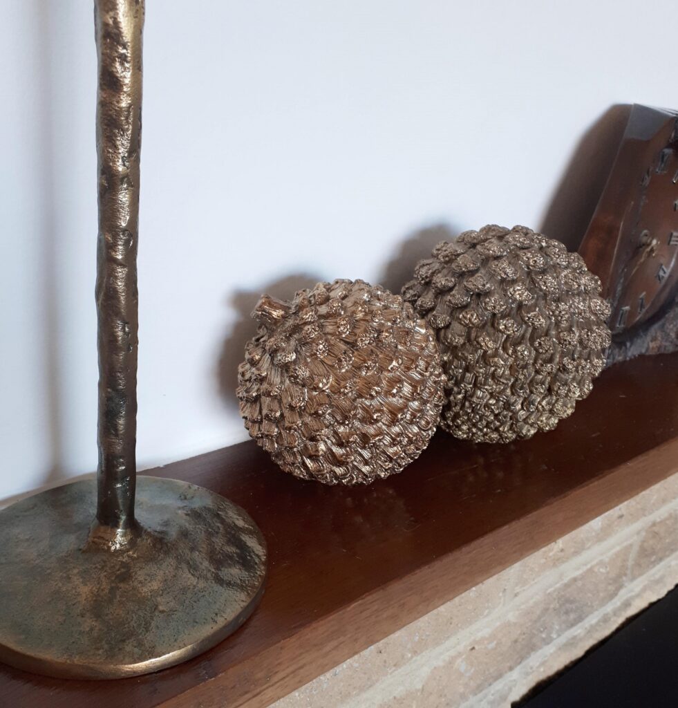Image of a mantel piece with two bronze round pinecones
