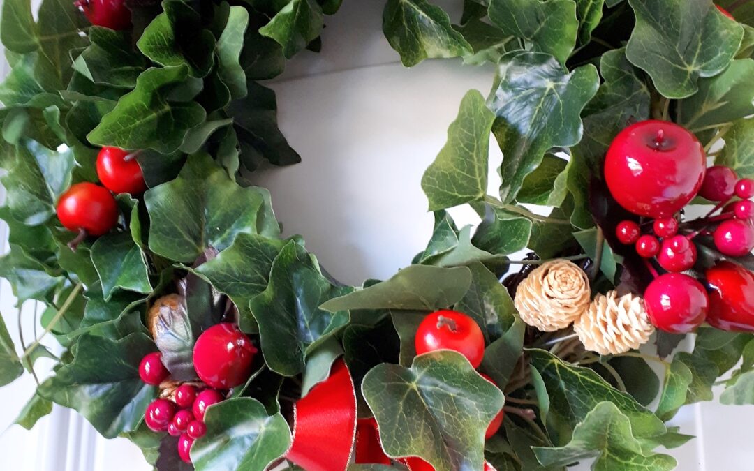 Image of a green ivy festive wreath with red faux fruits and belached mini pinecones