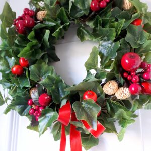 Image of a green ivy festive wreath with red faux fruits and belached mini pinecones