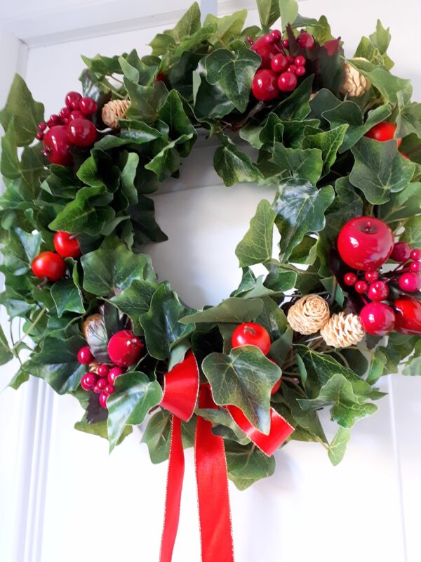 Image of a green ivy festive wreath with red faux fruits and belached mini pinecones