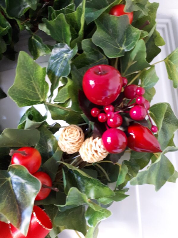 Details of the green ivy festive wreath, showing a close up of the faux red apples and pears