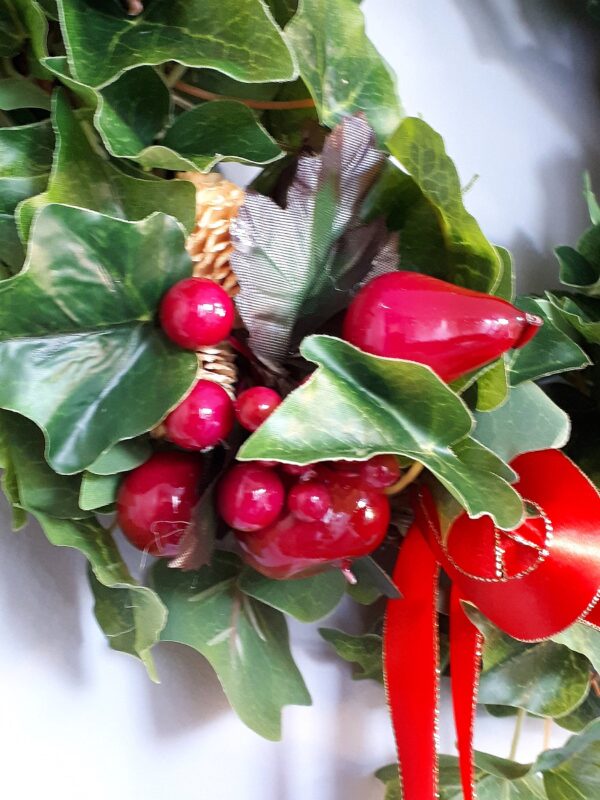 Details of the green ivy festive wreath, showing a close up of the faux red apples and pears