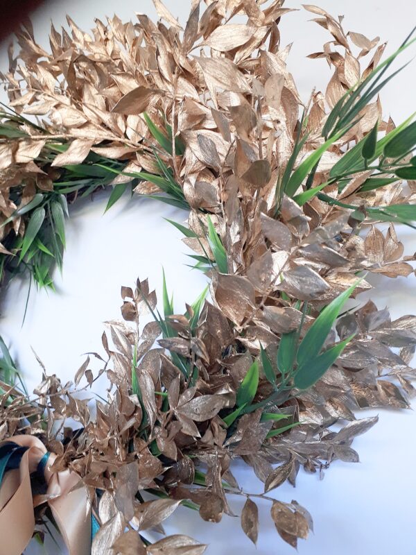 Detail of a bright gold ruscus luxury festive wreath with green accents