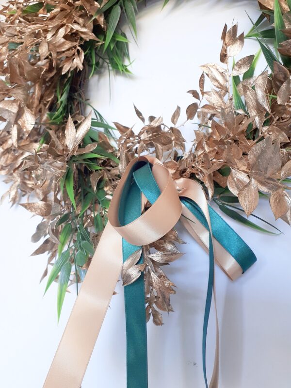 Details of a bright gold ruscus luxury festive wreath with green accents