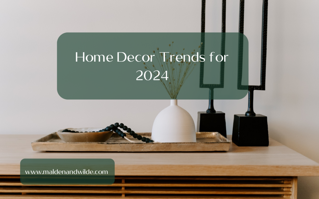 Image of wooden sideboard, with modern white ceramic vase 0n a wooden tray, and two black metal candlesticks. The picture title is Home Decor Trends for 2024