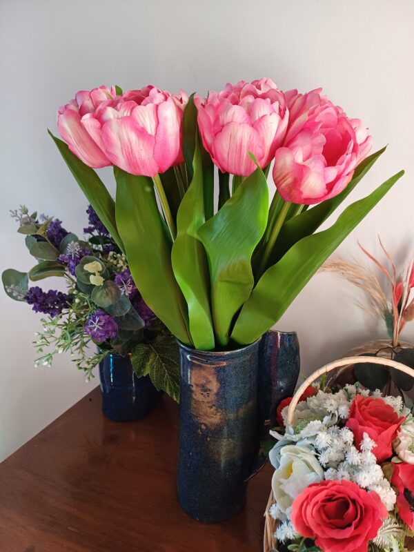 Pink variegated tulips in a dark blue ceramic vase