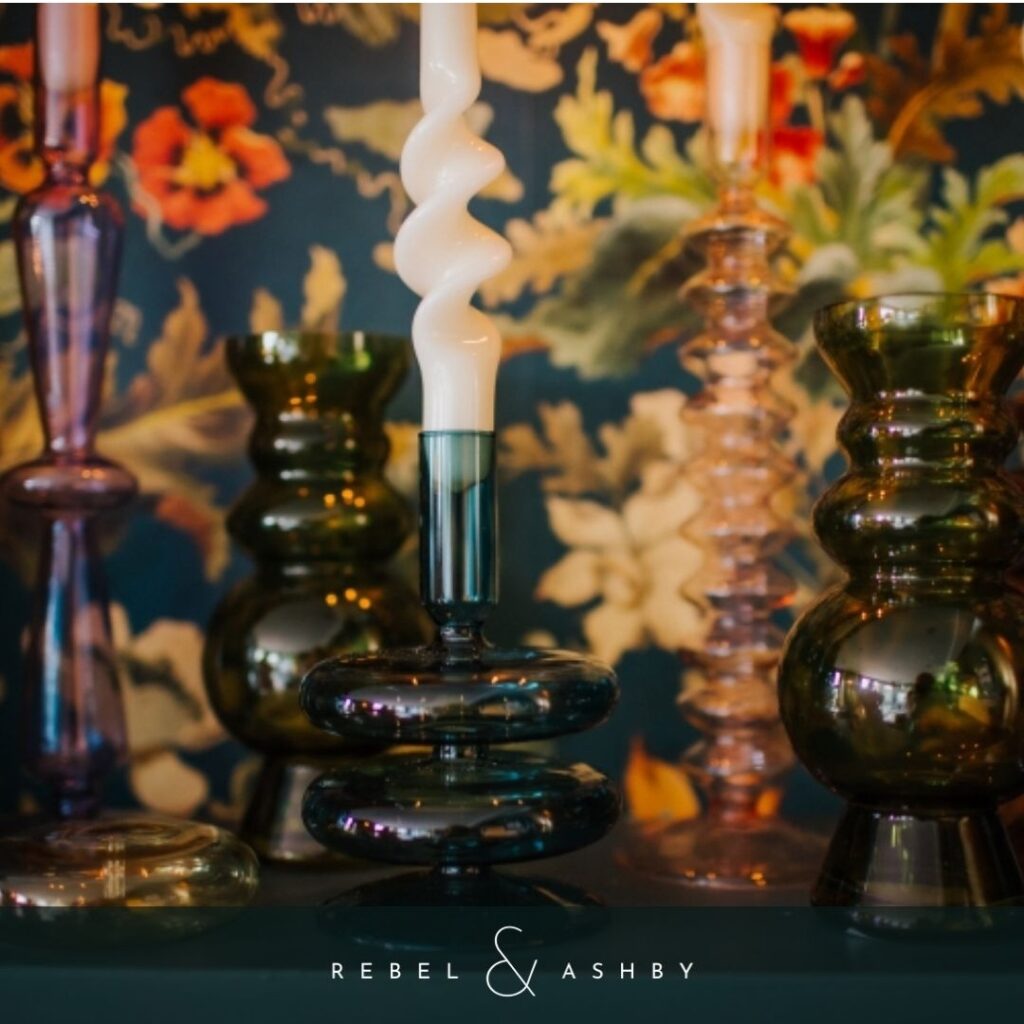 Image of glass candleholders in deep colours - green and purple - with white curly candlesticks