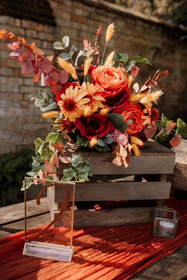 Image of bouquet of silk flowers in deep reds, orange and yellow.