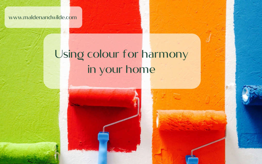 Image of four stripes of colour, green, red, orange and blue, being rolled onto a wall, to explore using colour for harmony on your home