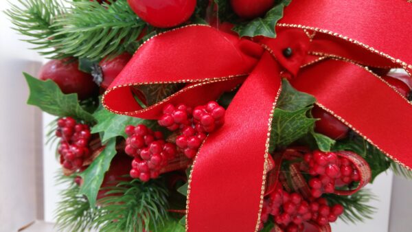 Detail of ball of faux red berries and holly leaves, with red ribbon