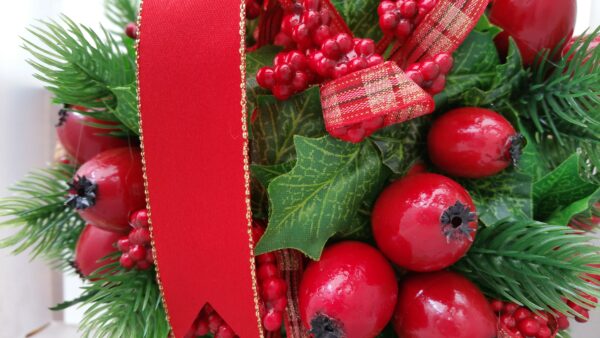 Detail of ball of faux red berries and holly leaves, with red ribbon