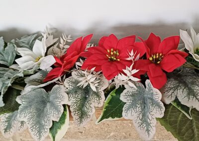 Red and white silk poinsettias, arranged with silver and green faux foliage, for a mantel piece decoration