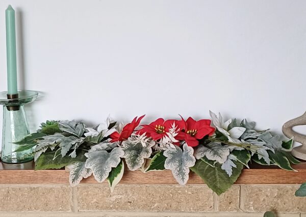 Res and wite silk poinsettia arrangement with silver and green foliage, for a mantelpiece.