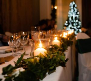 Image of a silk ivy garland lain the length of a wedding top table.  Pillar candles at intervals shine with a lovely glow