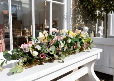 Spring silk flowers in a long arrangement on a wondowsill
