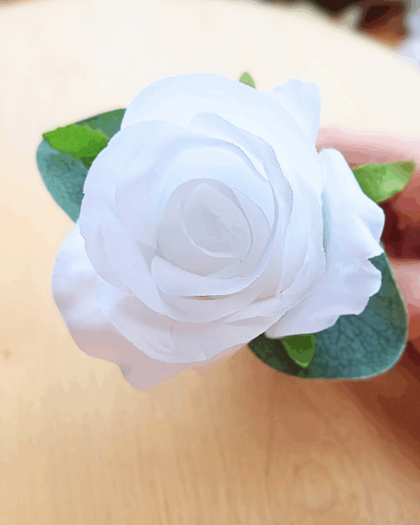 Close up of white silk rose Gorrom's buttonhole