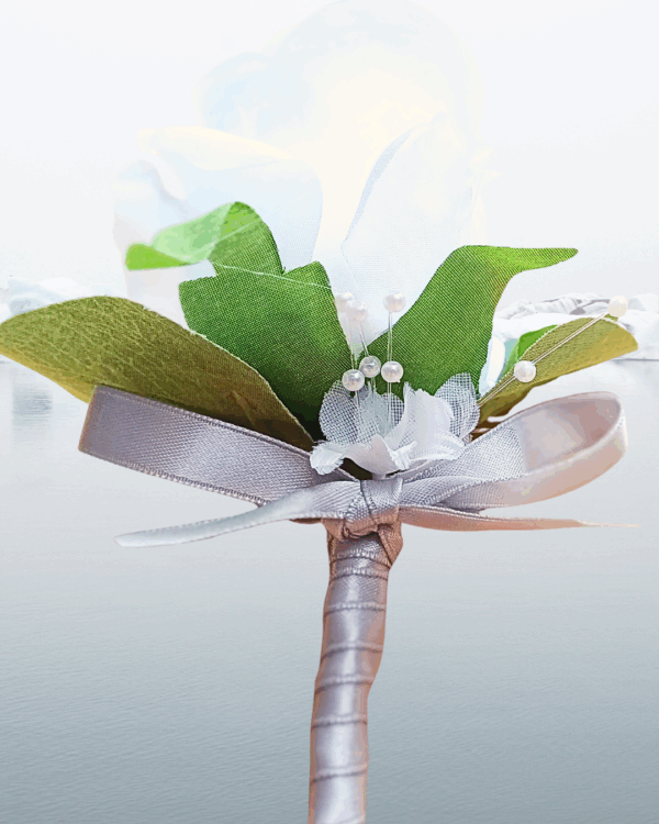 Image showing detail for a whote silk rose groom's buttonhole - silver ribbon, silk baby's breath flowers and silver bead.