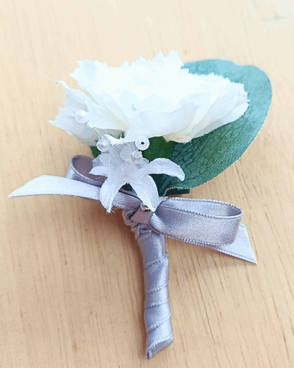 Image of pageboy mini buttonhole showing detail of carnation, silk baby's breath flower and silver satin bow.