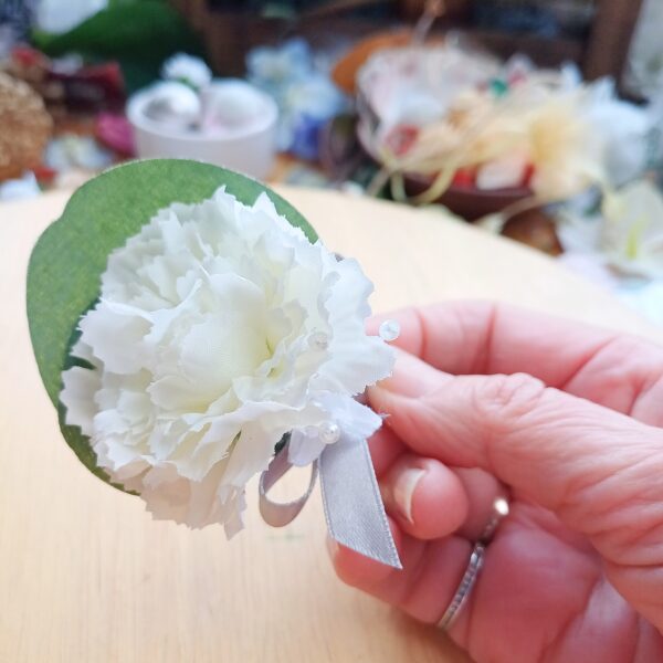 Image of pageboy mini buttonhole showing detail of small white silk carnation