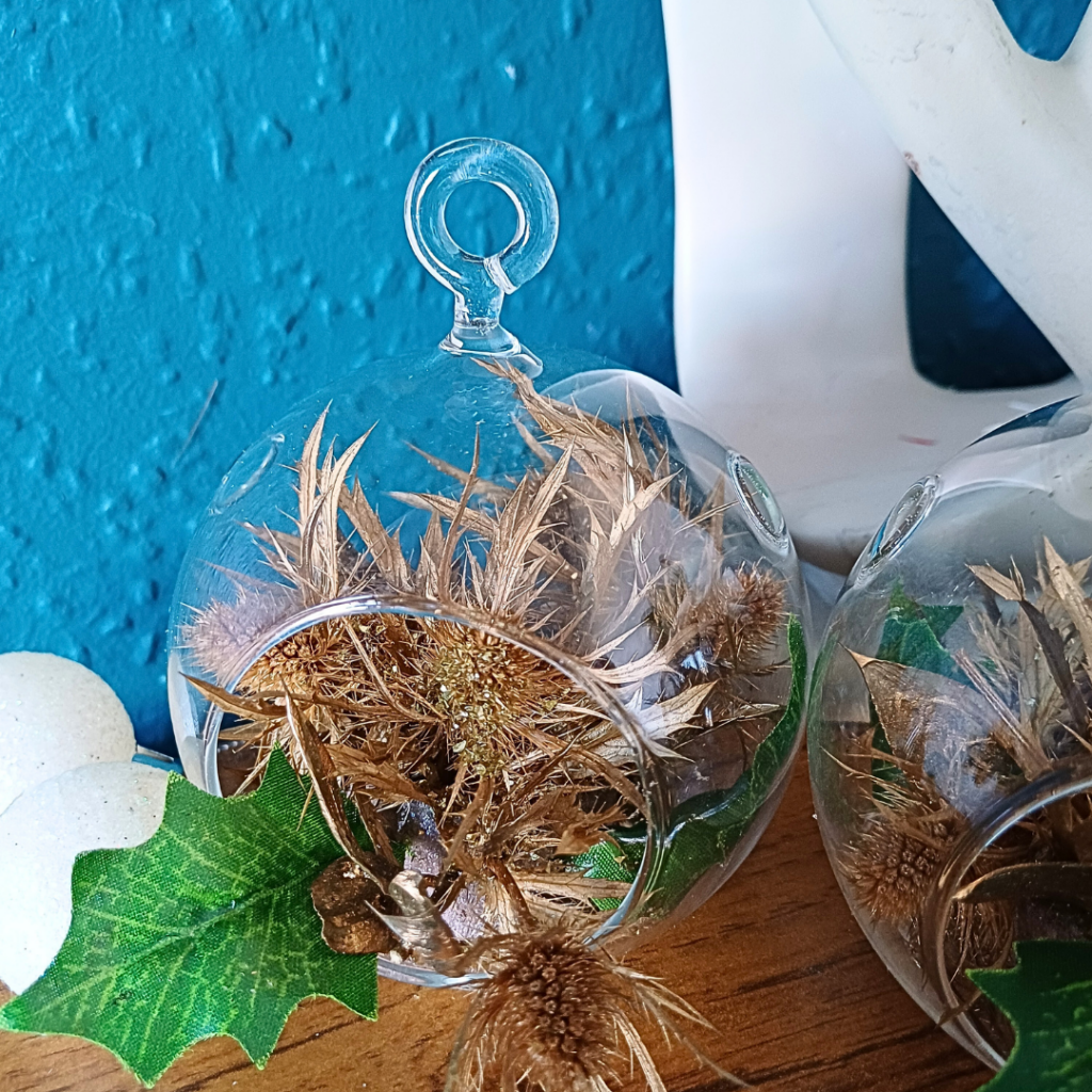 Glass globe ornament with gold preserved thistle flower