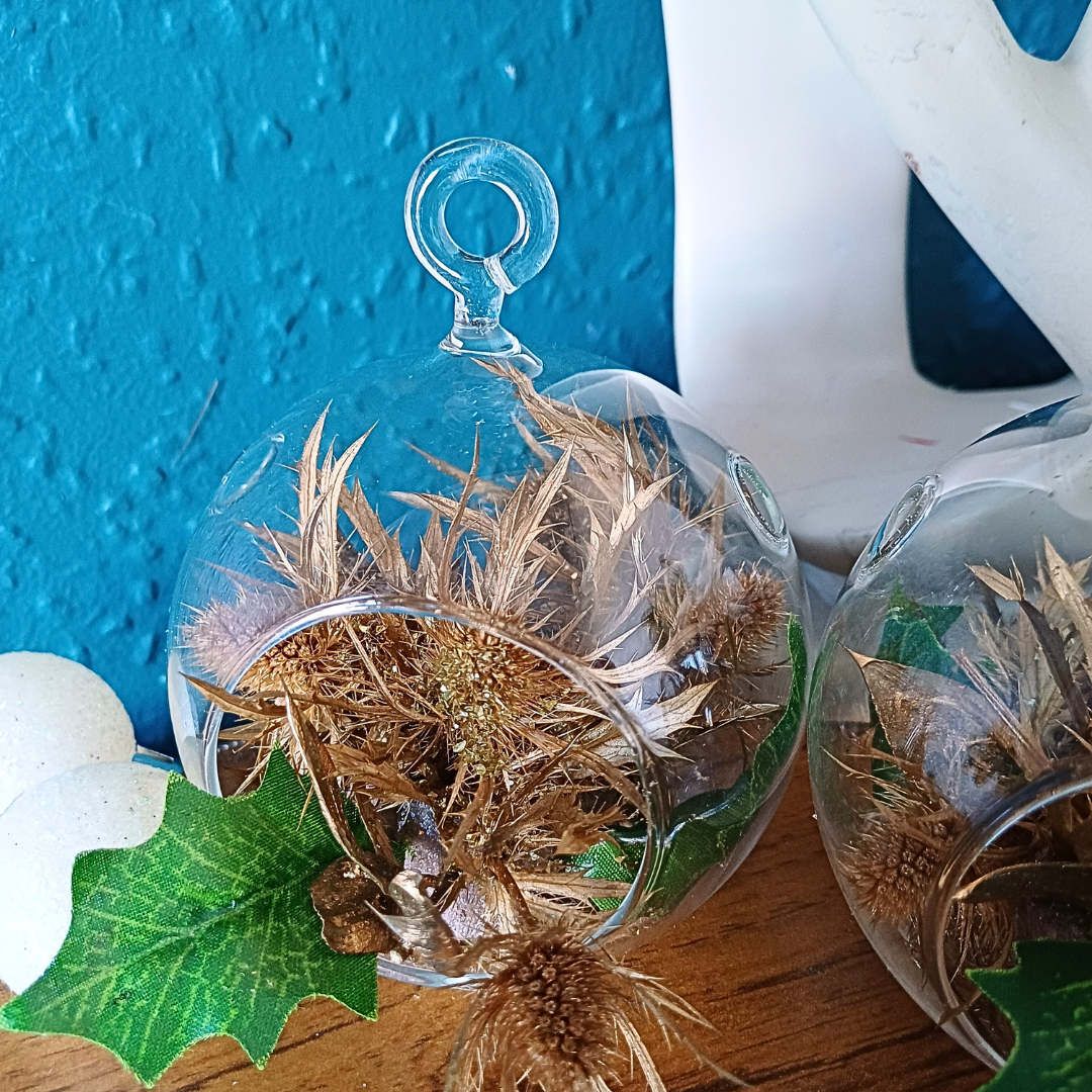 Glass globe ornament with gold preserved thistle flower