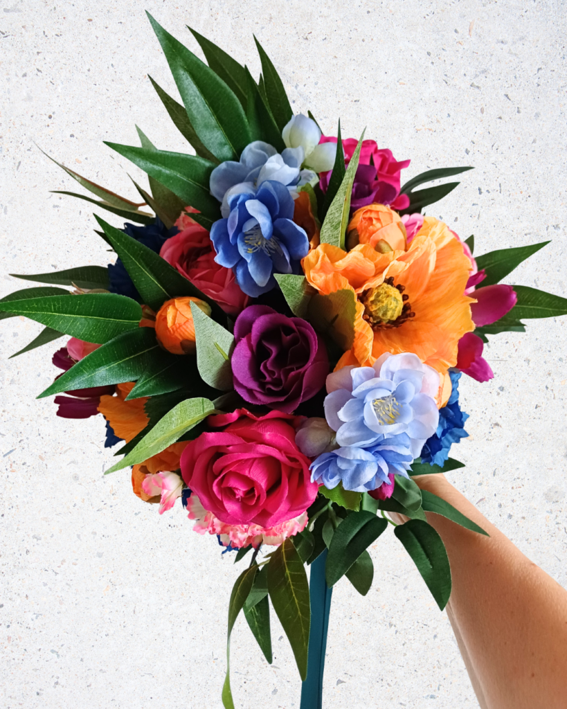 Bridal bouquet with bright flowers in orange, pale blue, purple, deep pink and with bright green foliage