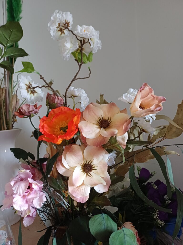 Mixed arrangement of silk flowers, red poppy, nude anemone, white apple blossom and pink cosmos