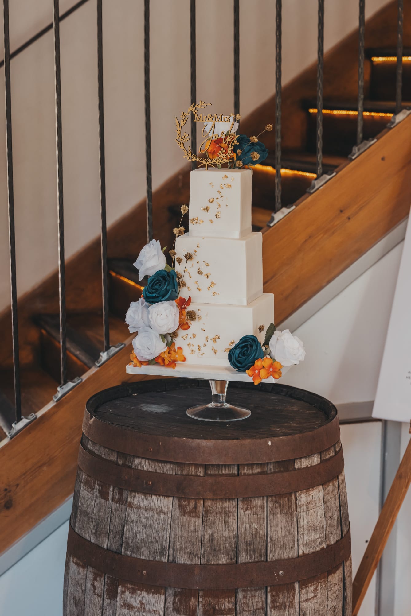 Wedding cake with teal and orange flowers and gold accents
